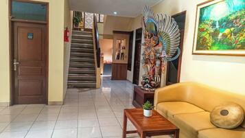 A hotel lobby with a staircase, a sofa, a coffee table, and a painting.
