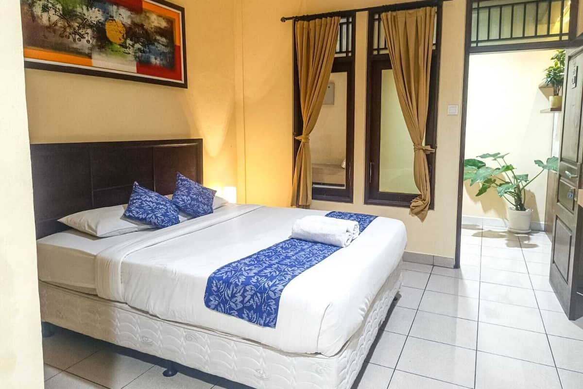 A hotel room with a bed, curtains, a painting, and a potted plant.
