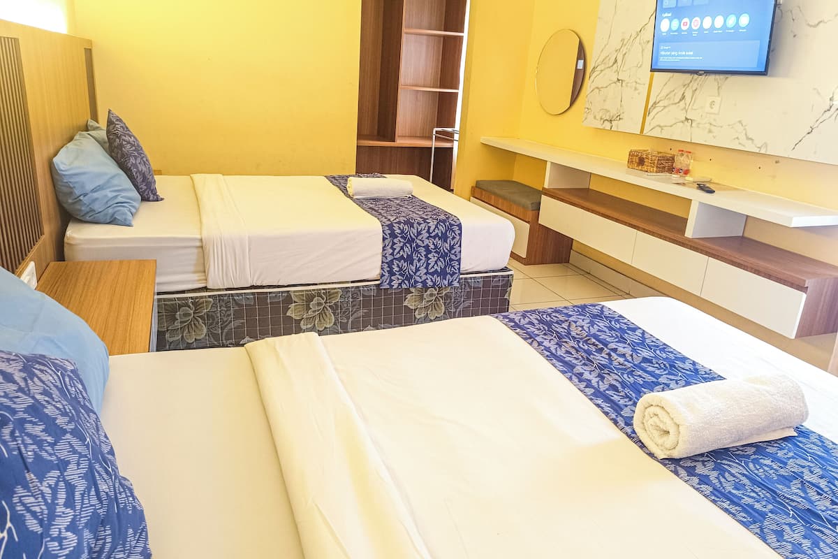 A hotel room with two beds, a TV mounted on the wall, and a wooden wardrobe.