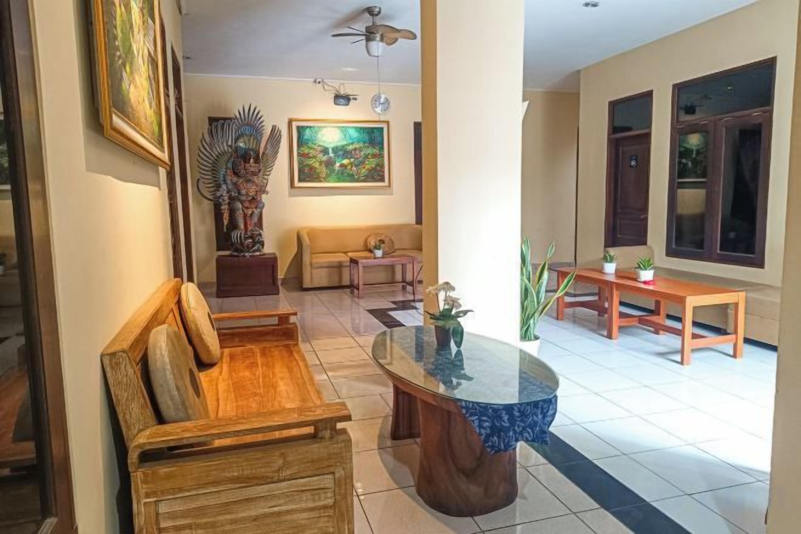 A living room with a wooden sofa, a glass coffee table, a painting, and a ceiling fan.