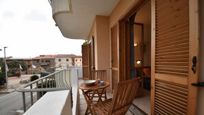 A balcony with a table and chairs, a railing, and a view of the street and buildings. - Three-room apartment downtown with two bathrooms and A/C (Santa Teresa Gallura)