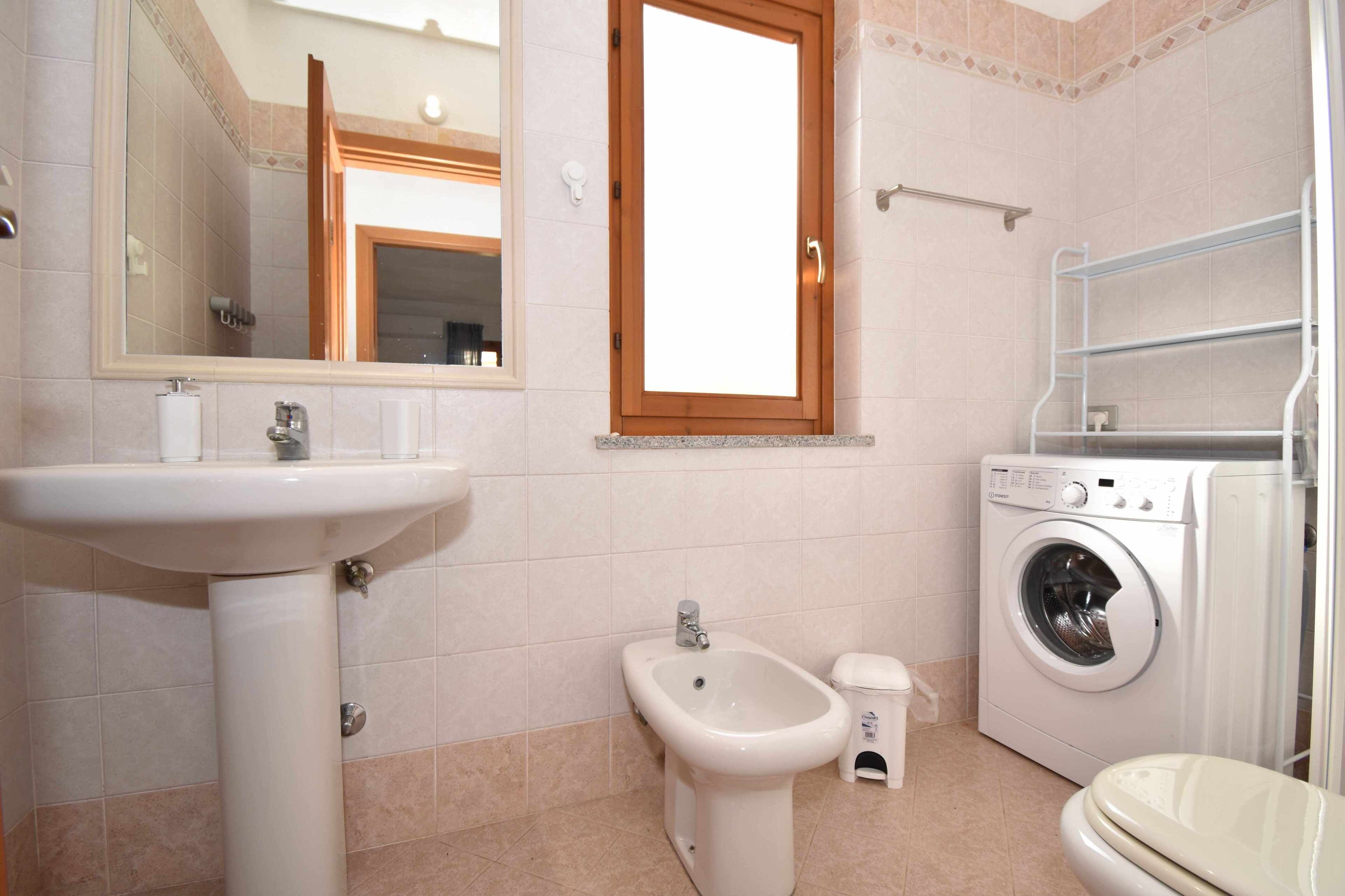 Une salle de bain équipée d’un lavabo, d’un bidet, d’un lave-linge et de toilettes.