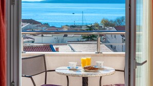 A balcony with a table set for breakfast, overlooking a coastal view.
