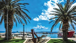 A marina with boats docked, palm trees, and a sculpture in the foreground.