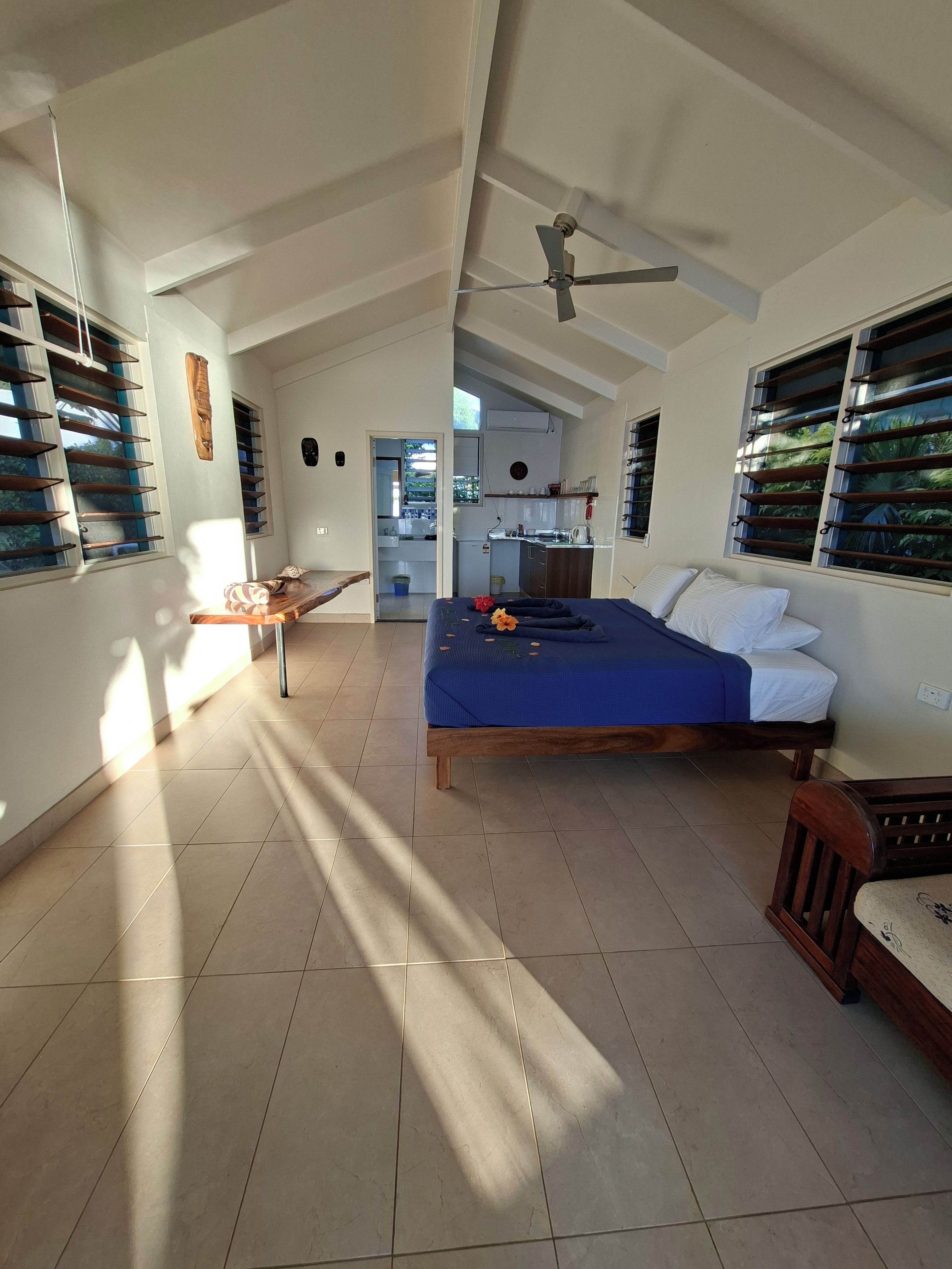 A spacious room with a bed, a desk, and a ceiling fan.