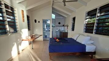 A spacious room with a bed, a desk, and a ceiling fan.