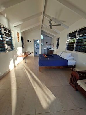 A spacious room with a bed, a desk, and a ceiling fan.