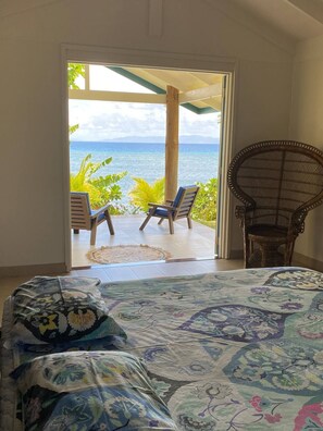 Un dormitorio con cama, una silla y vista al océano.