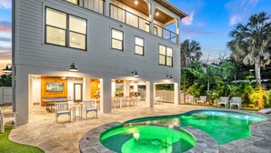 Une maison à deux étages avec une piscine et un espace extérieur aménagé pour se détendre.