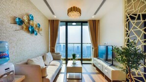 A modern living room with a sofa, coffee table, TV, and decorative wall art. - Vinhomes Skylake Managed by Anstay Residence (Hanoi)