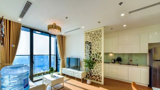 A modern living room with a large water dispenser, a TV, and a view of the city. - Vinhomes Skylake Managed by Anstay Residence (Hanoi)