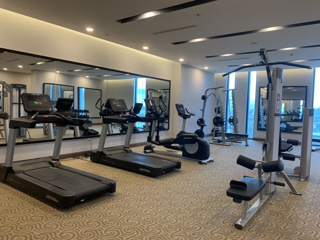Ein Fitnessstudio mit Laufbändern, Crosstrainern und Gewichten.