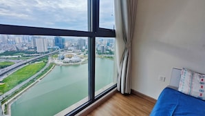 A room with a large window offering a view of a cityscape, a river, and a bridge. - Vinhomes Skylake Managed by Anstay Residence (Hanoi)