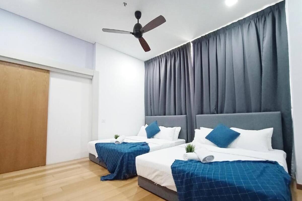 Ein Hotelzimmer mit zwei Betten, einem Deckenventilator und einem großen Fenster mit Vorhängen.