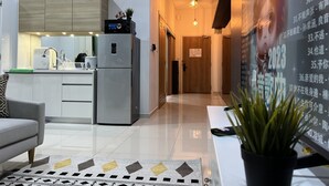 A modern kitchen with a refrigerator, microwave, and sink. There is a sofa and a potted plant in the living area. - Desa Parkcity Plaza Arkaida Suite KL (Kuala Lumpur)