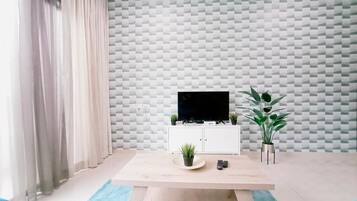 Una sala de estar moderna con un televisor sobre un mueble blanco, un tapete azul y una pared con diseño.