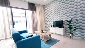 A modern living room with a blue sofa, a coffee table, a flat-screen TV, and a potted plant. - Desa Parkcity Plaza Arkaida Suite KL (Kuala Lumpur)