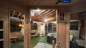 A wooden interior with a digital clock, a hot tub, and a green carpeted area. - The Mara Waterfront Cottage, Muskoka
 (Huntsville)