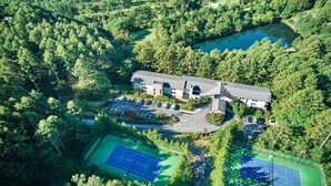 An aerial view of a property with a large building, a parking area, and two tennis courts surrounded by dense forest. - Tokyu Vacations Tateshina (Chino)