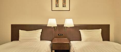 A hotel room with two beds, a nightstand with lamps, and a framed artwork on the wall.