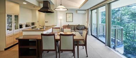 A modern kitchen with a dining area, large windows, and a balcony.