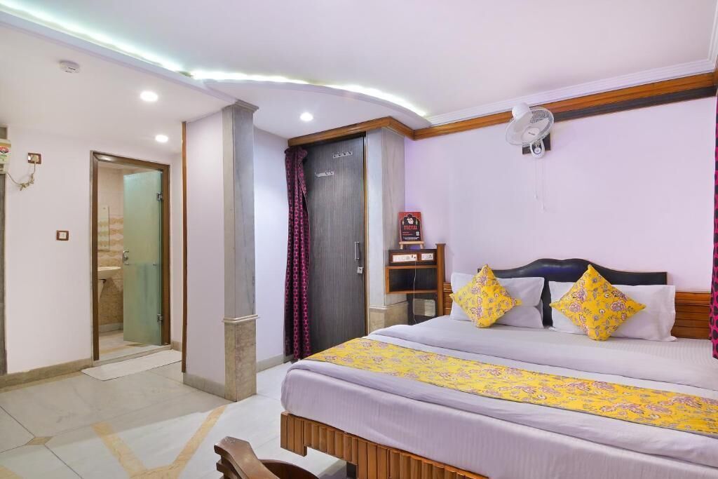 Una habitación de hotel con cama, mesita de noche y ventilador.