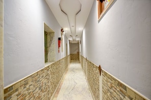 Corridors feature polished floors and patterned tile walls, with recessed lighting and framed artwork.
