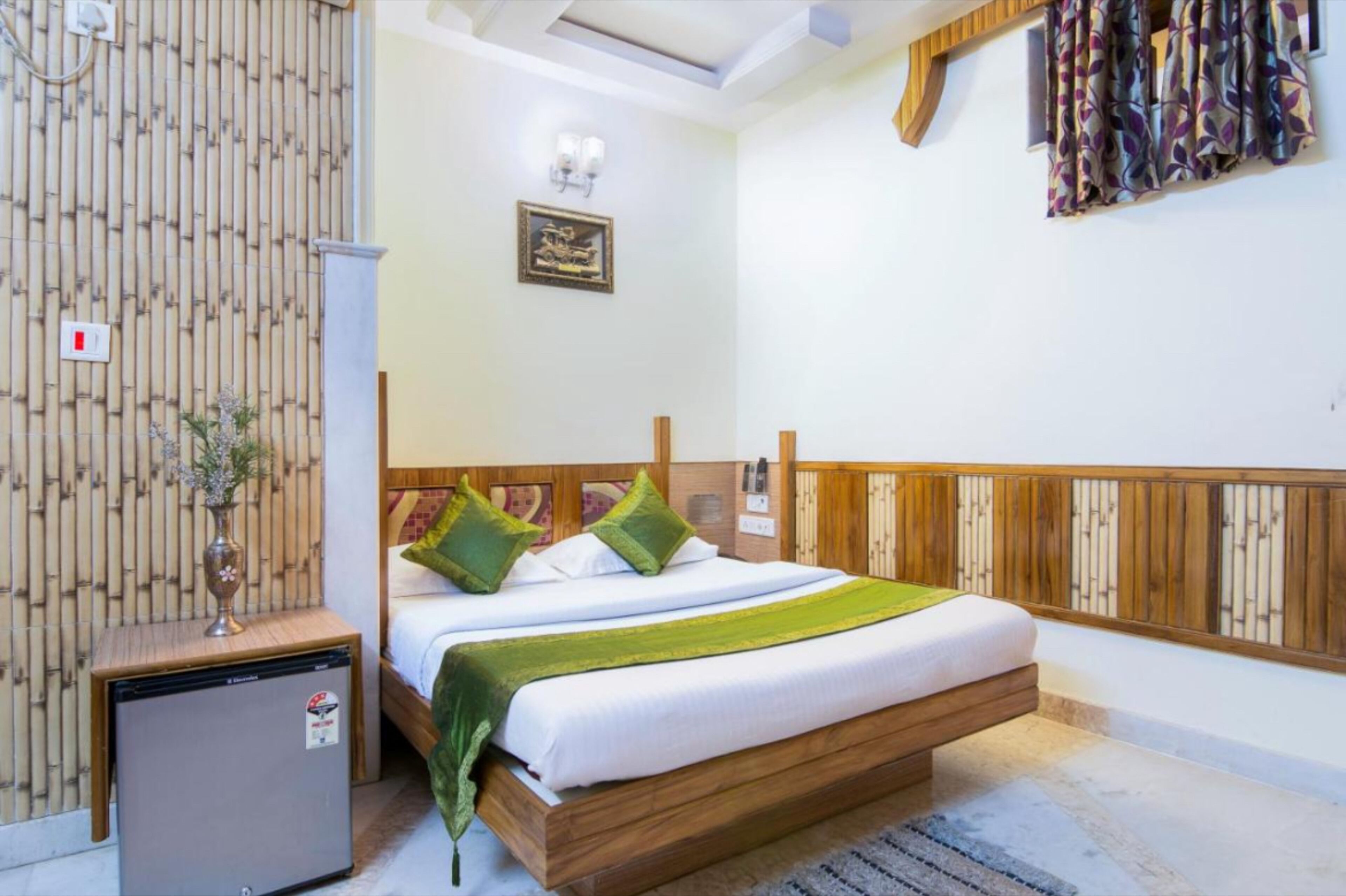 A bedroom with a bed, bedside table, and a small refrigerator.