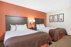 A hotel room with two beds, a nightstand with lamps, and framed pictures on the wall. - ASPEN HOTEL ROGERS -FORMERLY AMERICINN (Rogers)