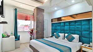 A modern hotel room with a large bed, a flat-screen TV, a desk, and a window with curtains. - The Bella Vista – Traveler's Choice Awarded (New Delhi)