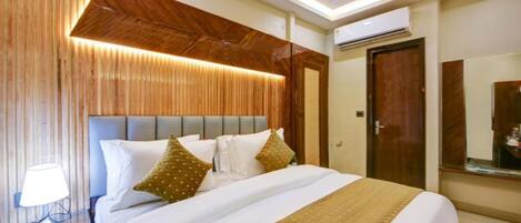 A hotel room with a bed, bedside table, lamp, and a wooden accent wall.