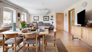 Een ruime woonkamer met een eettafel, stoelen, een bank en een televisie.