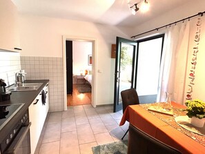 A compact kitchen with a sink, stove, and dining area with a table set for two.
