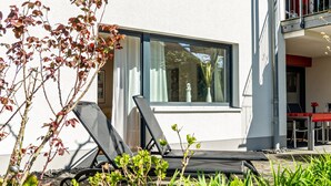 Een modern gebouw met een balkon, buitenmeubels en een raam met gordijnen.