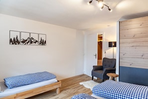 Een kamer met een bed, een stoel, een houten wand en een deur naar een andere kamer.