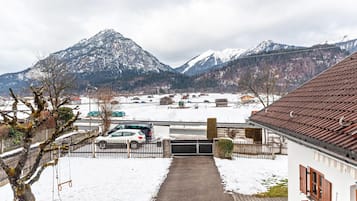 Et boligområde med et sneklædt landskab, et bjerg i baggrunden og et hus med tegltag.