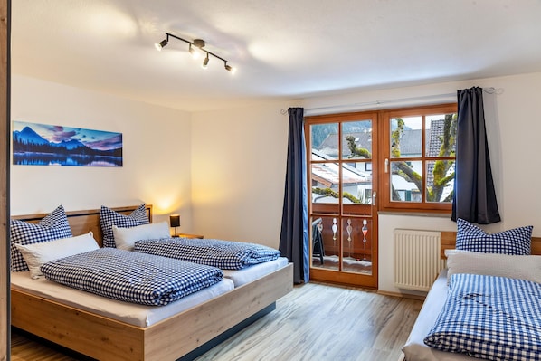Een kamer met twee bedden, een raam met gordijnen, een schilderij aan de wand en een plafondlamp.