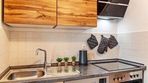 Une cuisine moderne avec des meubles en bois, un évier en acier inoxydable, un four encastré et une bouilloire.