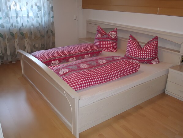 A bedroom with a bed, nightstands, and a window with curtains.