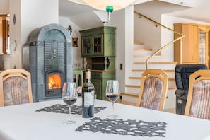 A dining area with a fireplace, a table set with wine glasses and a bottle, and a staircase in the background. - Holiday Apartment 'Schwarzwalduhren Nescht Triberg' with Panoramic View (Triberg)