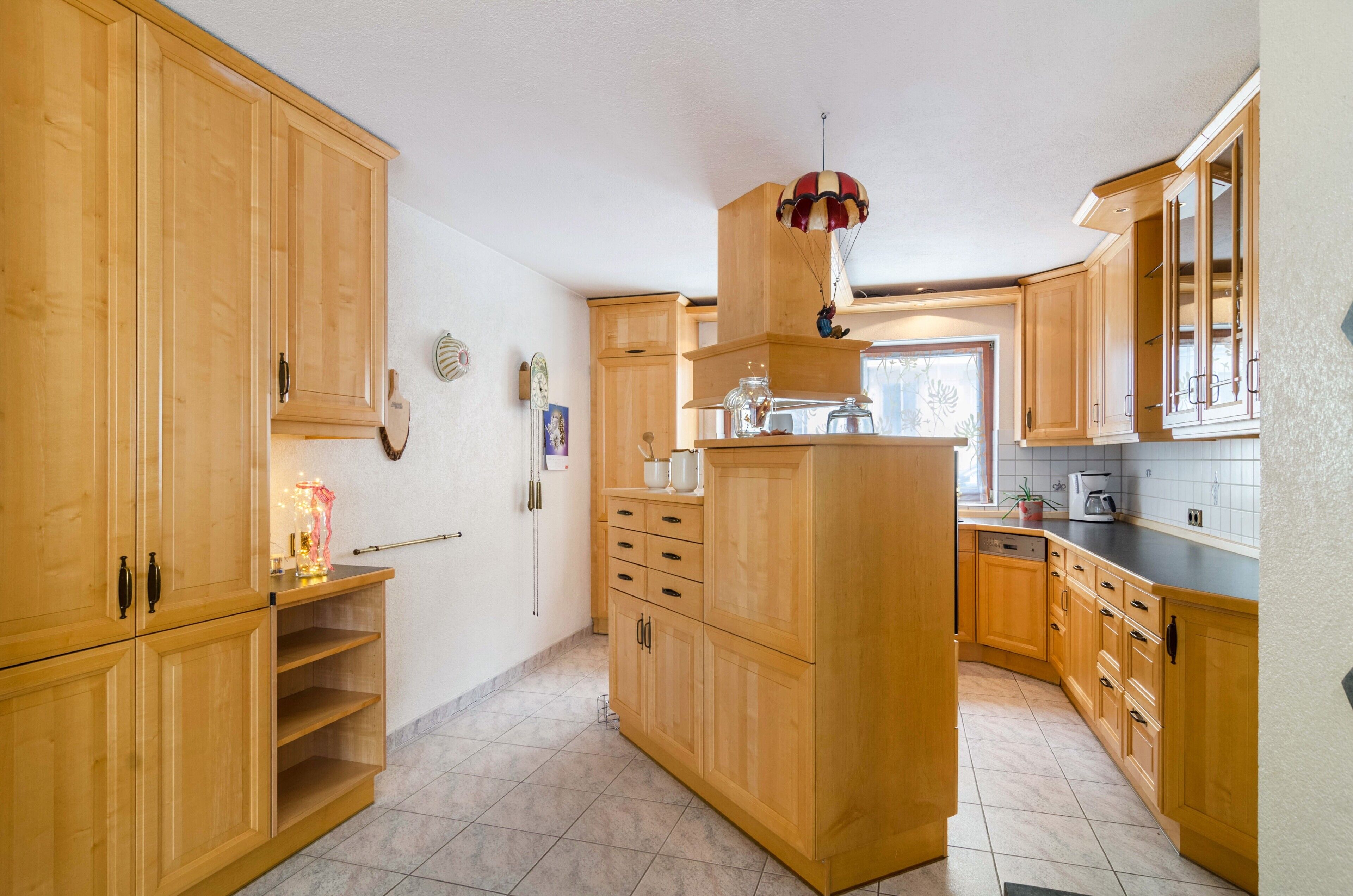 A kitchen with wooden cabinets, a central island, and a hanging light fixture.