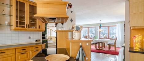 Una cocina con armarios de madera, encimera de granito y comedor con alfombra roja.