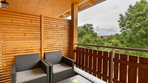 A balcony with wicker furniture, a table with a candle, and a wooden fence. - Apartment 'Ferienwohnung Gauchach' with Shared Garden, Balcony and Wi-Fi (Löffingen)