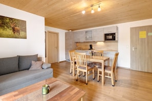 Une cuisine moderne avec des meubles en bois, une table à manger avec des chaises, un canapé et un tableau représentant un cerf accroché au mur.