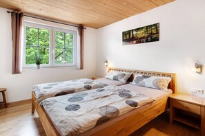 Une chambre à coucher avec un lit en bois, une table de chevet, une fenêtre avec des rideaux et un tableau au mur.