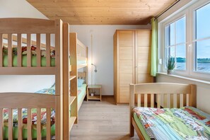 Quarto com beliches, guarda-roupa, mesa de cabeceira e janela com vista.