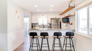 A modern kitchen with a central island, bar stools, and built-in appliances.