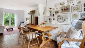Uma sala de jantar com mesa de madeira, cadeiras e luminárias pendentes.