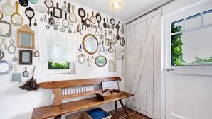 Um quarto com um banco de madeira, cestos de vime e diversos espelhos e molduras na parede.