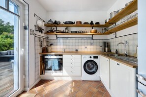 A compact kitchen with a washing machine, a built-in oven, and a sink. - Holiday Home 'Ferienhaus Karinella' with Private Terrace, Private Garden and Wi-Fi (Scharbeutz)